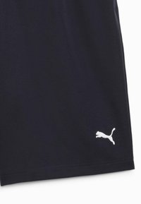 Section de vêtement noir avec logo Puma blanc brodé près du bord inférieur sur le côté droit.