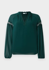 Mørkegrønn bluse med lange ermer og gjennomsiktige ermer, blondekant over overarmene, rynket hals og en V-formet åpning ved brystet.