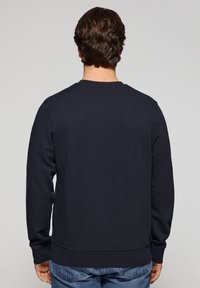 Marineblauwe sweatshirt met lange mouwen, een ronde hals en geribde boorden. Zachte textuur, ontspannen pasvorm, minimaal ontwerp zonder zichtbare patronen.