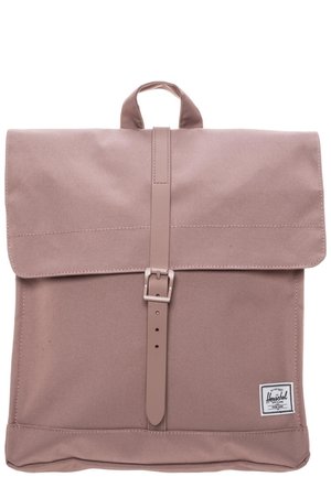 Vaalean liilanvärinen kangasreppu, jossa on yläkansi keskellä olevan solkilenkin avulla suljettuna ja pieni logoplässi oikeassa alakulmassa.