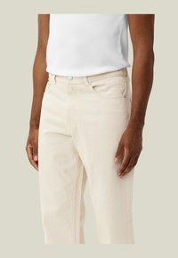Pantaloni in denim beige con design a gamba dritta, dotati di chiusura frontale con bottone, passanti per cintura e due tasche laterali.