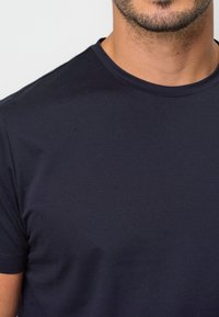 Mörkblå t-shirt gjord av mjukt, slätt tyg med rund halsringning och korta ärmar; har en enkel design utan mönster eller dekorationer.