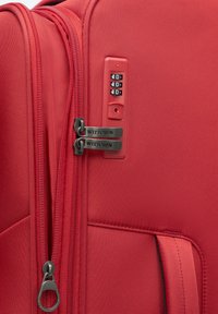 Maleta roja con exterior texturizado, doble cremallera y un candado de combinación. Presenta herrajes negros y un bolsillo lateral para almacenamiento adicional.