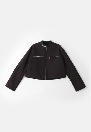 Veste noire courte en tissu texturé, avec des fermetures éclair argentées sur les poches avant, un col rond et des manches longues.