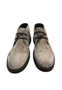 Scarpe in suede grigie con punta rotonda, due asole per i lacci e suola in gomma nera. Presentano una texture liscia e un design minimalista.