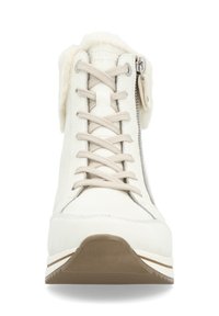 Botte d'hiver blanche avec lacets beiges, fermeture éclair latérale et doublure en fourrure douce visible autour de la cheville, vue de face.