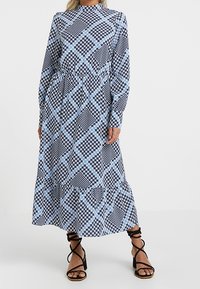 Långärmad klänning i medellängd med ett geometriskt mönster i svart, vitt och ljusblått, rund halsringning och samlad midja.