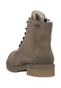 Botas de ante marrón con cordones, forradas con forro de lana, logotipos de marca en el costado y suela de goma gruesa.