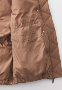 Braune, gesteppten Jackeninnenseite mit glatter Textur, ausgestattet mit einer Tasche und bedruckten Symbolen, die Eigenschaften anzeigen: recycelt, wasserabweisend, leicht.