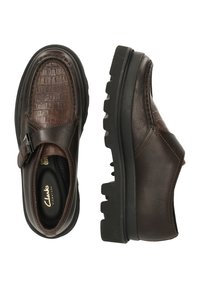 Braune Lederschuhe mit Krokodilstruktur im Obermaterial, die über eine Schnallendetail und eine robuste schwarze Gummisohle verfügen.