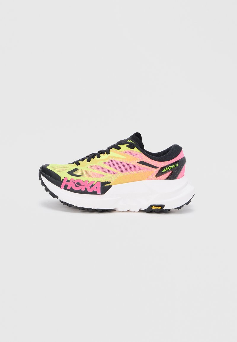 Scarpa da corsa HOKA gialla brillante e rosa con lacci neri, suola spessa bianca e etichetta "Mafate X" sul tallone su uno sfondo bianco neutro.