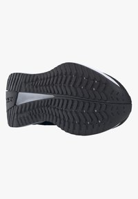 La suela de zapato de goma negra presenta un patrón texturizado con surcos diagonales, una leve curvatura hacia el talón y un acento suave en el arco.