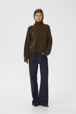 Brown knitted turtleneck sweater with relaxed fit, paired with dark blue wide-leg jeans. Smooth texture with minimal detailing and no visible accents.