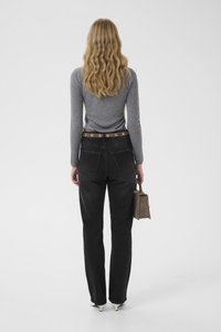 Halligad pikkade varrukatega särk, mustad kõrge vö�ökohaga teksad nähtavate tagataskutega, pruun vöö hõbedaste detailidega, hoides väikest pruuni käekotti.