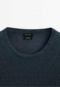 Maglione lavorato a maglia di colore blu scuro con scollo rotondo. Realizzato in 100% lino, presenta una texture liscia e una piccola etichetta con i dettagli del marchio all'interno.
