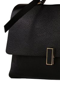 Zwarte leren handtas met een gestructureerde afwerking, met een stevige vorm, gouden beslag en een klep als sluiting. Verstelbare riem inbegrepen.