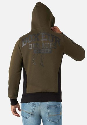 Hoodie vert olive avec des accents noirs, arborant un grand logo gris imprimé dans le dos. Il a une capuche et des poignets côtelés.