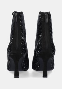 Botines negros de tacón con parte superior de malla texturizada, cierre de cremallera y tacón cónico. Principalmente de ante suave alrededor de la base.
