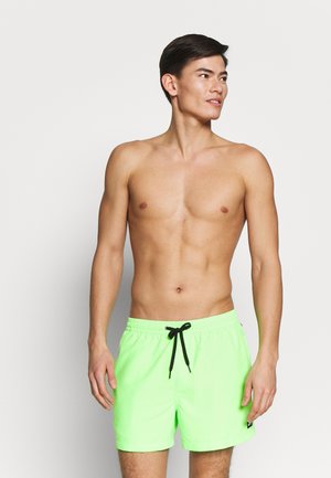 Bañador verde neón con cintura ajustable por cuerda, que incluye un cordón negro y bolsillos laterales para mayor funcionalidad.