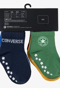 Due paia di calzini per bambini: uno navy con testo "CONVERSE" bianco e motivo a stelle, l'altro verde con un logo circolare e dettagli a stelle.