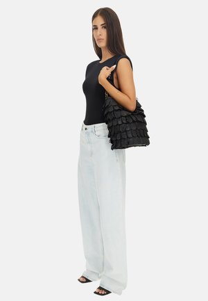 Black scalloped handbag with gold hardware, paired with black fitted top and light blue wide-leg jeans. Smooth texture, detailed design.