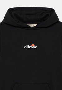 Melns kapucis ar auklu. Raksturīga ar baltu "ellesse" logotipu un krāsainu akcentu virs tā. Mīksta tekstūra un brīvs piegriezums.