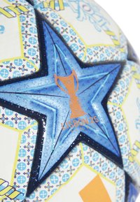 Blauwe en witte voetbal met een sterontwerp. Heeft een gestructureerd oppervlak, een oranje trofee-logo en kleurrijke geometrische patronen.