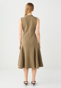 Abito senza maniche color khaki con orlo svasato, realizzato in tessuto testurizzato. Presenta un collo alto e cuciture visibili lungo la schiena.