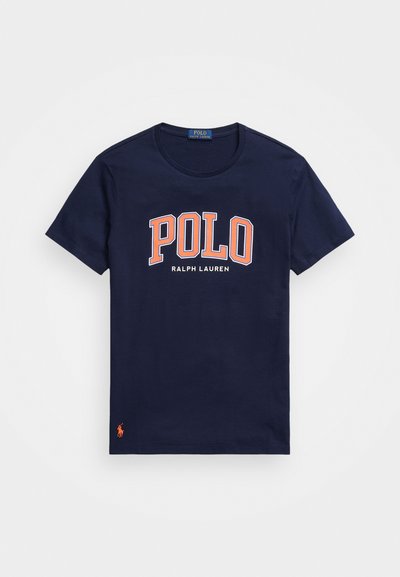 T-shirt de algodão azul-marinho com gola redonda. Apresenta um grande gráfico "POLO" em laranja e o texto "RALPH LAUREN" abaixo. Pequeno logótipo na bainha.