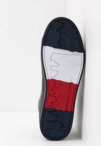 Zwarte schoenzool met een veelkleurig ontwerp: marineblauwe, witte en rode secties met graphics van de skyline en het Vrijheidsbeeld.