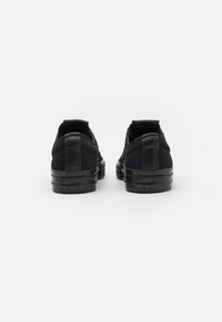 Czarne zamszowe sneakersy niskie z gładką fakturą, wyposażone w czarną gumową podeszwę i wytłoczone logo na pięcie.