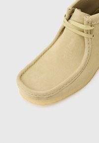 Μπεζ μπεζ σανδαλοειδές παπούτσι μοκασίνι από καστόρι με σόλα κρεπ και στρογγυλεμένη μύτη, με μπεζ κορδόνια και ορατό ράψιμο κατά μήκος των άκρων.