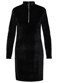 Schwarzes, langärmliges Kleid aus weichem, plüschigem Stoff mit hohem Kragen und einem silbernen Reißverschluss am Hals. Taillierte Passform.