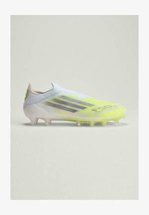 White and neon yellow soccer cleat with black stripes and studded sole, shown in side profile on plain light background.