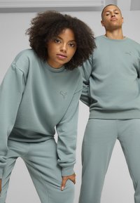 Lys grønne sweatshirts og matchende bukser lavet af blødt stof; har afslappet pasform og broderet logo på brystet.