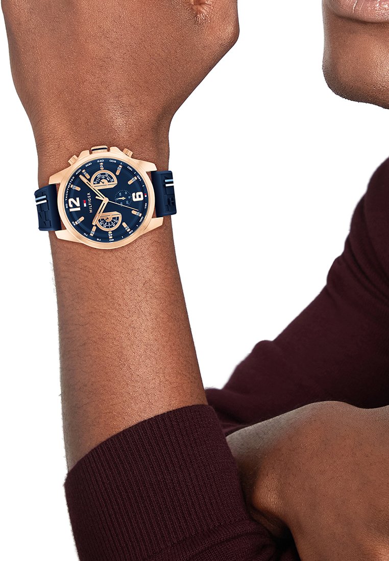 Zegarek na silikonowym pasku w kolorze granatowym z różowozłotą kopertą, okrągłą tarczą z białymi znacznikami godzin, wyświetlaczem daty i dwoma subtarczykami.