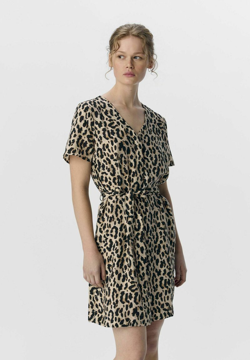 Robe à imprimé léopard, manches courtes, décolleté en V, taille cintrée avec une ceinture, tissu doux, fond beige avec des taches noires.