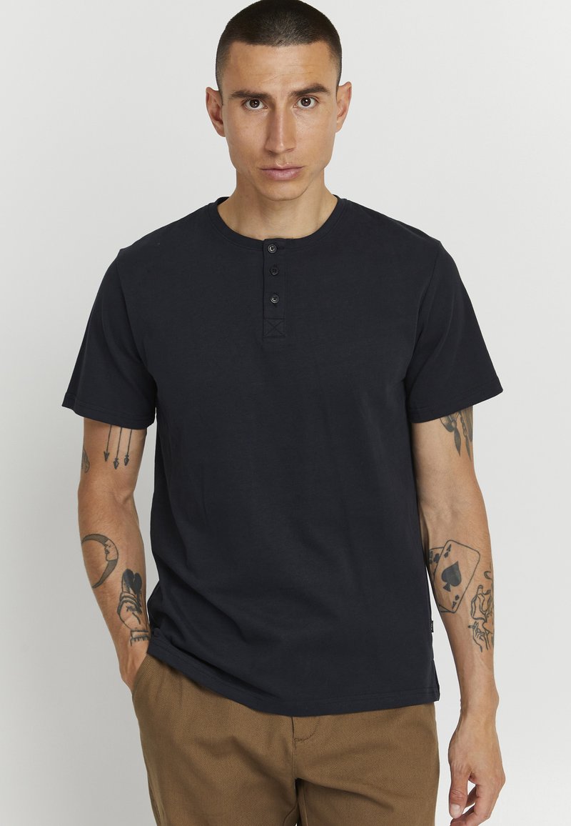 T-shirt henley nero con scollo rotondo, patta con tre bottoni e maniche corte. Realizzato in cotone con una trama liscia.