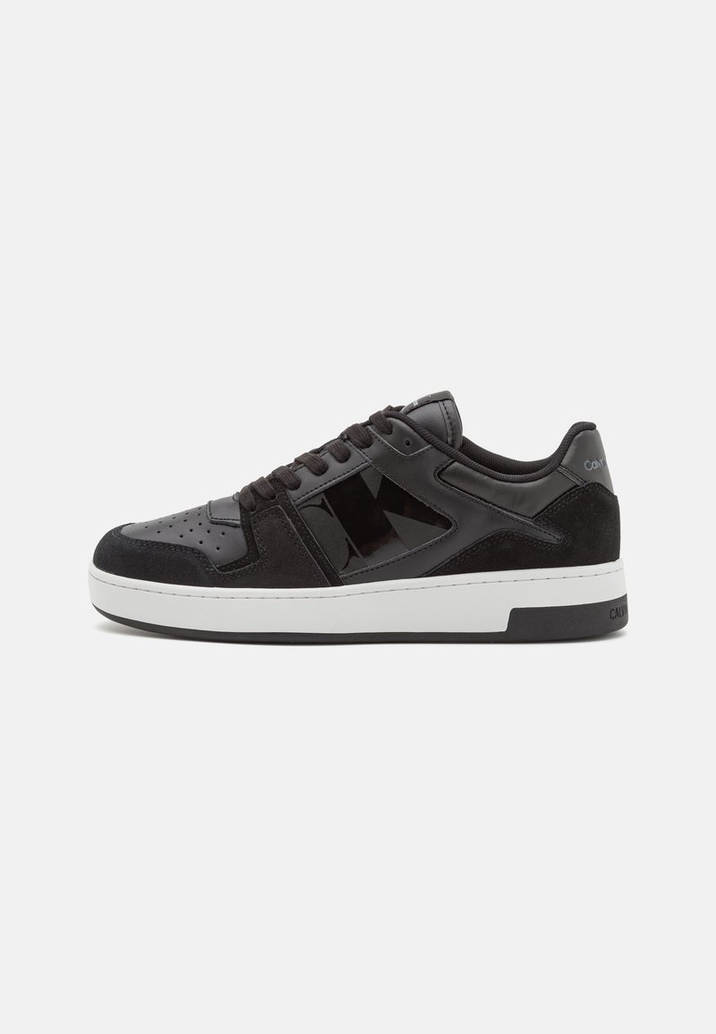 Zapatillas negras que combinan cuero liso y ante, diseño minimalista, medioboleta blanca y acentos recortados distintivos.