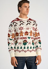 Gebreide feestdagen trui met een crème basis en rode en groene feestelijke patronen, waaronder peperkoekmannetjes, zuurstokken en kerstbomen.