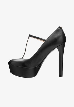 Chaussure noire à talon haut avec bride T et bout rond, finition en cuir lisse, et talon stiletto fin sur fond blanc.
