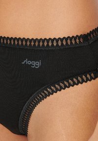 Slip neri di cotone con bordo in pizzo, caratterizzati da un delicato motivo a intaglio lungo l'elastico in vita e un'etichetta con logo sul lato.