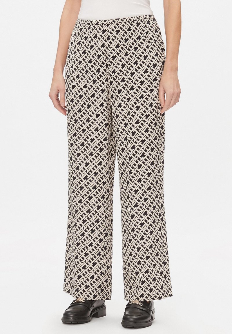 Pantaloni a gamba larga con un motivo geometrico in bianco e nero, realizzati in un materiale leggero con una texture liscia. Vita elasticizzata.