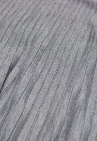 Tissu gris avec texture côtelée verticale et légères rides à la surface.