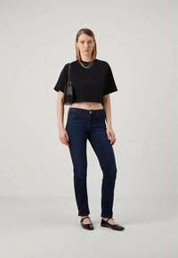 Must musta T-särk, tume sinine kitsas teksapüksid ja mustad plätud. Metallist kettkaelakee, väike õlakott. Lihtne, igapäevane riietus.