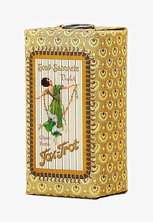 Violet soap packaging with a decorative gold and brown pattern. Features an illustration of a figure in green, holding flowers and surrounded by clouds.