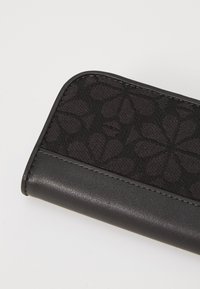 Black leather wallet featuring a textured fabric panel with a floral pattern, contrasting stitching, and rounded edges.