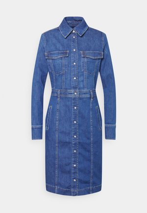 Džínová košilová šaty ve středně modré barvě s dlouhými rukávy, dvojitými náprsními kapsami, zapínáním na knoflíky a páskem v pase. Rovný střih se švy.