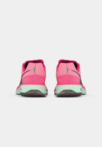 Une paire de chaussures de course roses et menthes montrées de l'arrière sur un fond blanc, mettant en évidence les talons et les semelles.