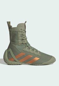 Zapatilla deportiva alta de color verde oliva con rayas de cobre, tela texturizada, cordones detallados y soporte de talón acanalado distintivo.